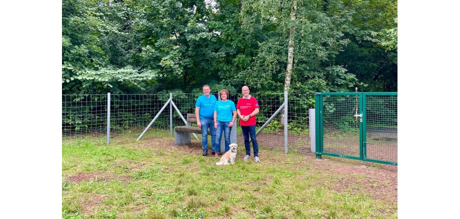 v.l.n.r.: Bereichsleiter Horst Helmes, Karina Daub von Westenergie und Oberbürgermeister Dirk Meid freuen sich über die Realisierung eines Hundelaufplatzes, welcher jeden Vierbeiner zum Verweilen einlädt 3 Personen stehe auf einem Rasen vor einem Zaun
