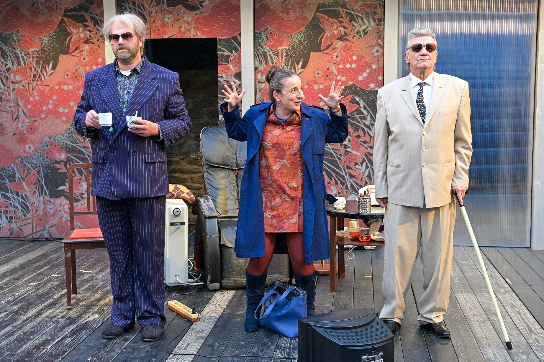 Zwei Männer mit Sonnenbrille und eine Frau in der Mitte stehen auf einer Bühne