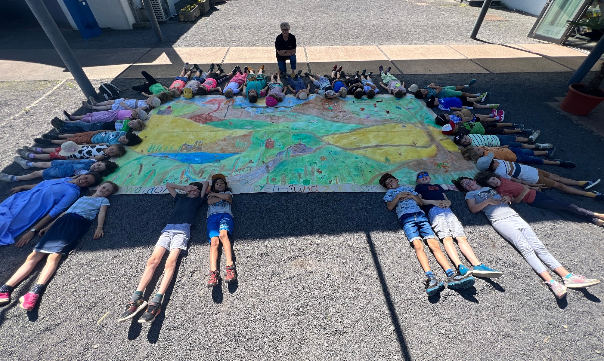 Viele Kinder liegen um ein großes Bild herum 