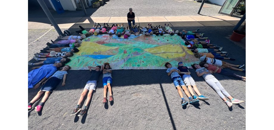 Viele Kinder liegen um ein großes Bild herum 