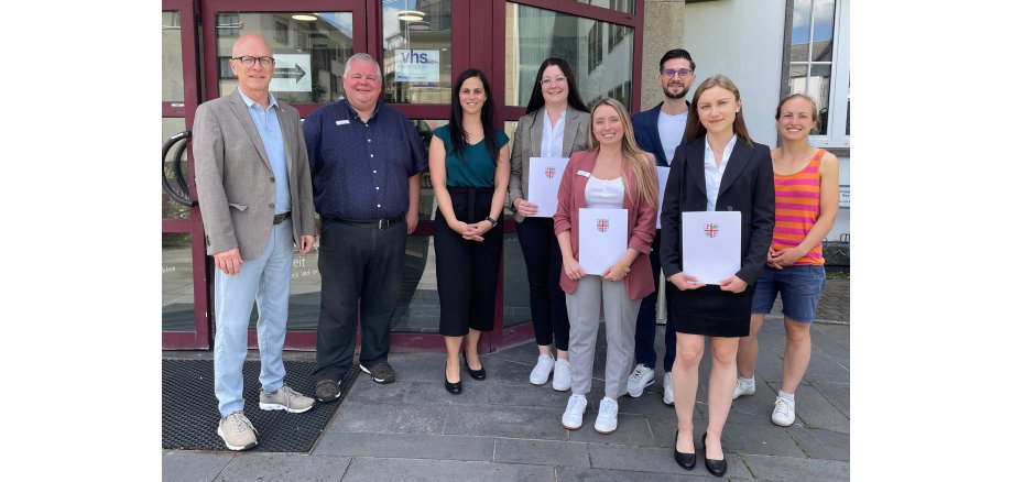 8 Personen stehen vor dem Eingang des Rathauses - einige halten eine Urkunde in den Händen