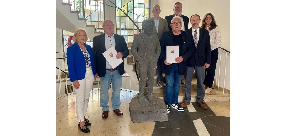 v.l.n.r.: Hannelore Knabe, Norbert Knabe, Oberbürgermeister Dirk Meid, Hans Jakob Molitor, Hans-Jürgen Gross, Joachim Anheier und Anke Hinterholz-Britscho 7 Personen stehen im Eingangsbereich des Rathauses - in der Mitte der Mayener Jung aus Stein