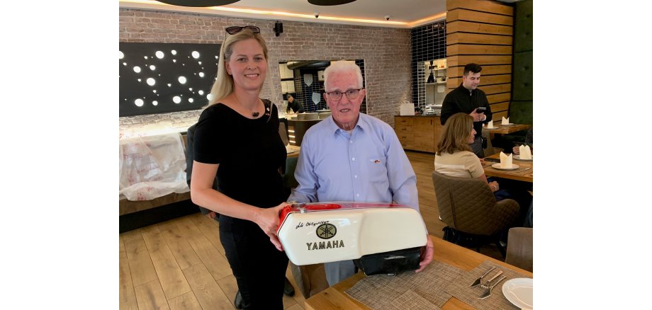 Eine Frau und ein Mann mit einem Tank eines Motorrades in den Händen