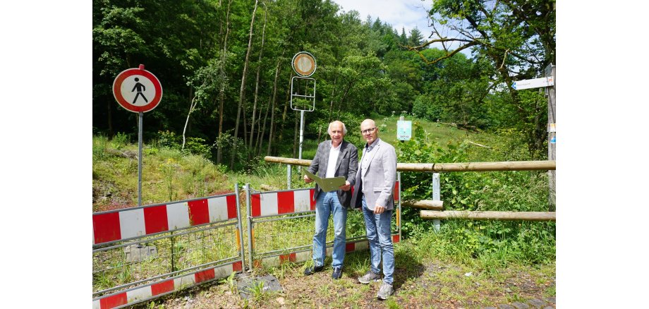 2 Männer stehe mit einem Plan an einer Baustelle