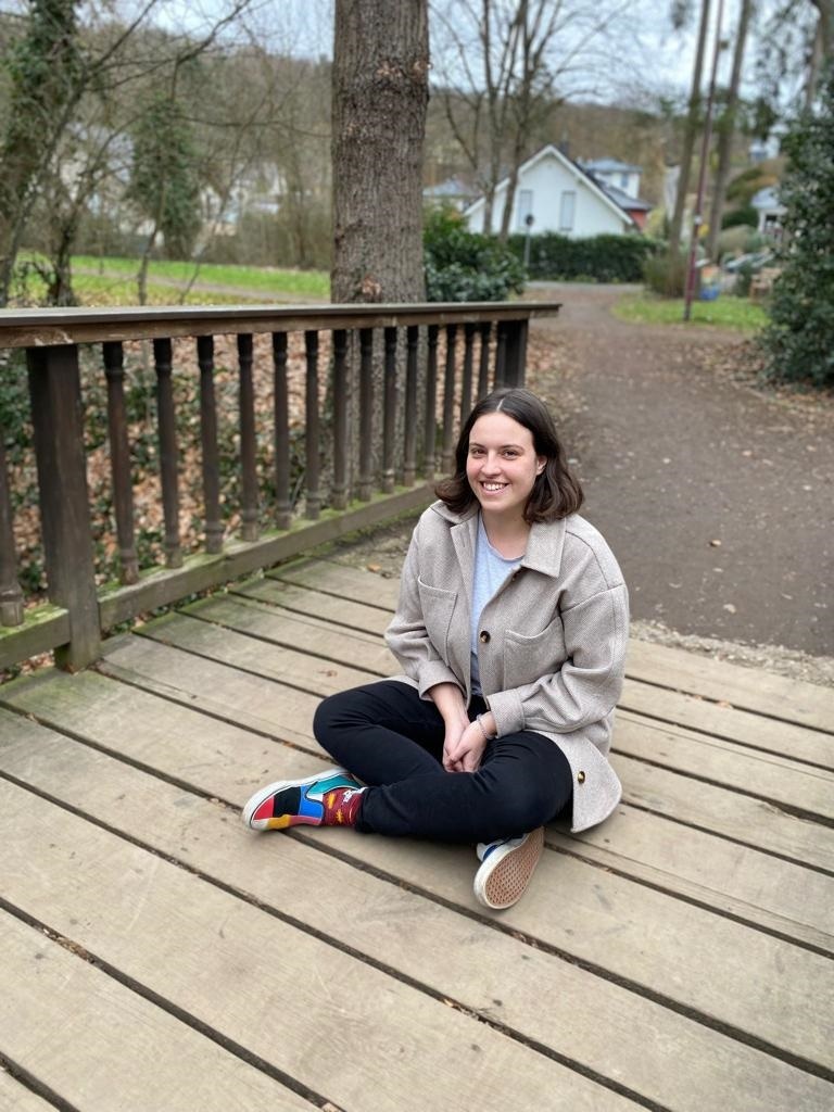 Frau sitzt im Schneidersitz auf einer Brücke