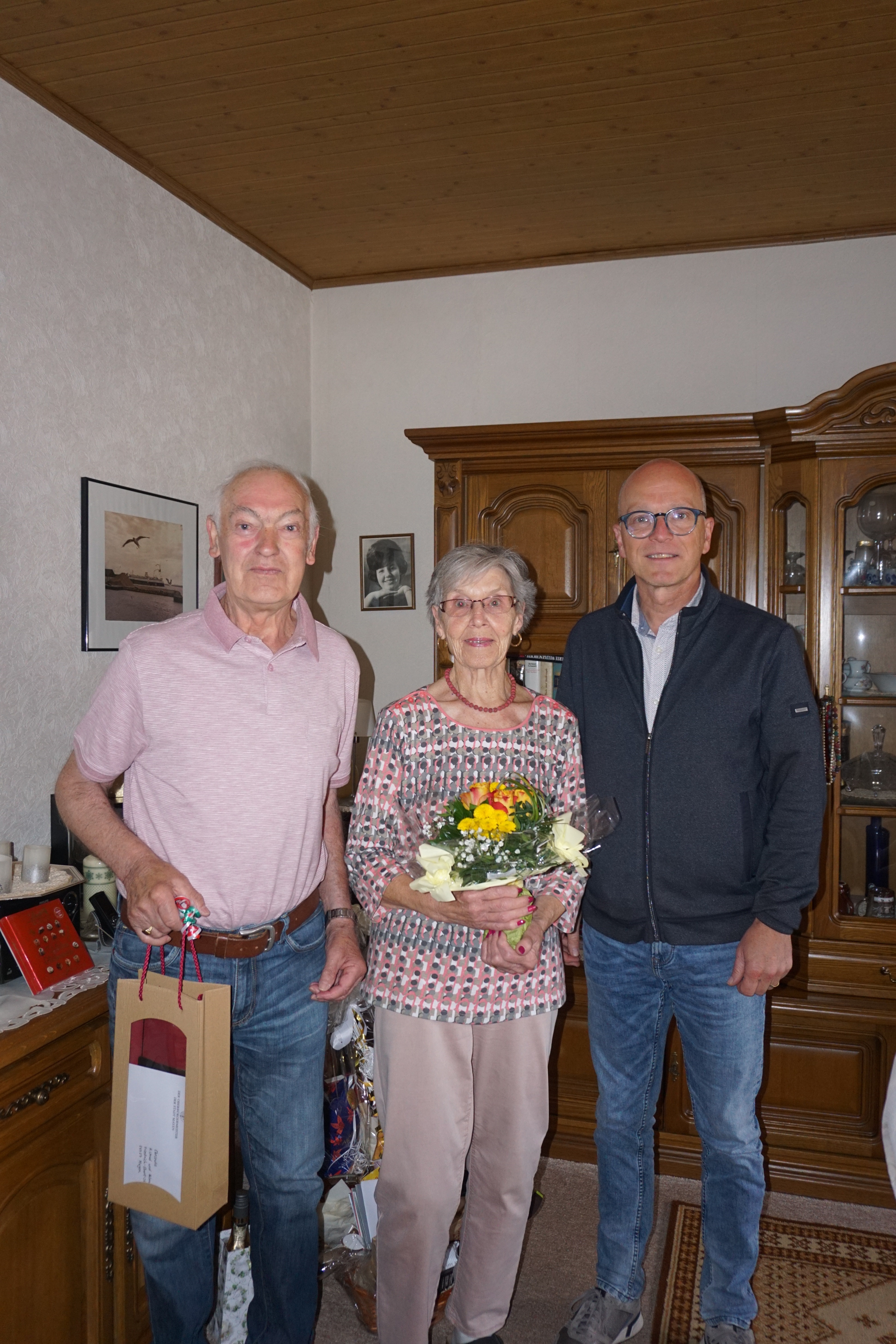 2 Männer und eine Frau in der Mitte mit einem Blumenstrauß