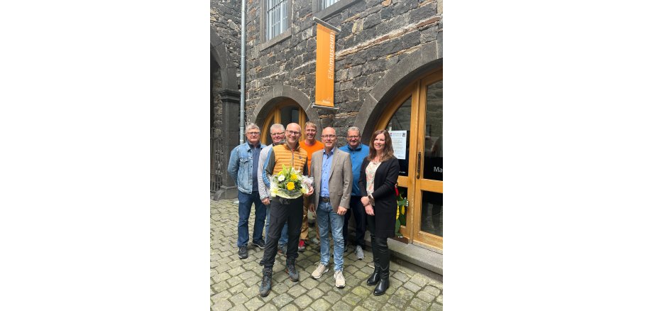 Sieben Personen stehen vor dem Eingang des Eifelmuseums - einer hält einen Blumenstrauß in den Händen