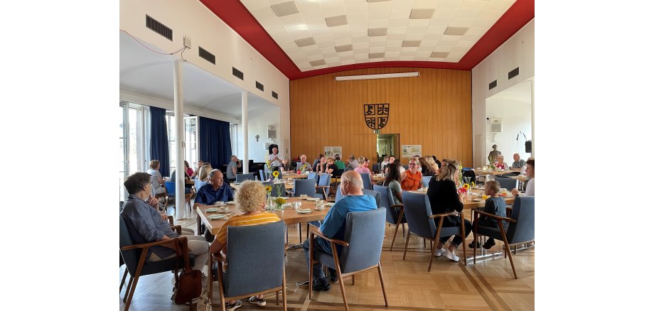 Viele Menschen sitzen an Tischen und frühstücken
