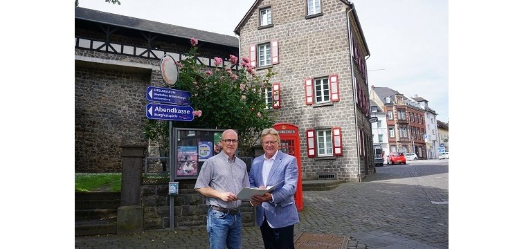 2 Männer stehen mit einer Mappe in der Hand zusammen
