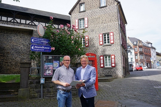 2 Männer stehen mit einer Mappe in der Hand zusammen