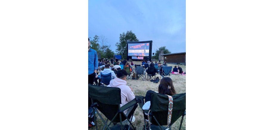 Viele Besuchende auf der Wiese beim Open-Air Kino im Mayener Grubenfeld