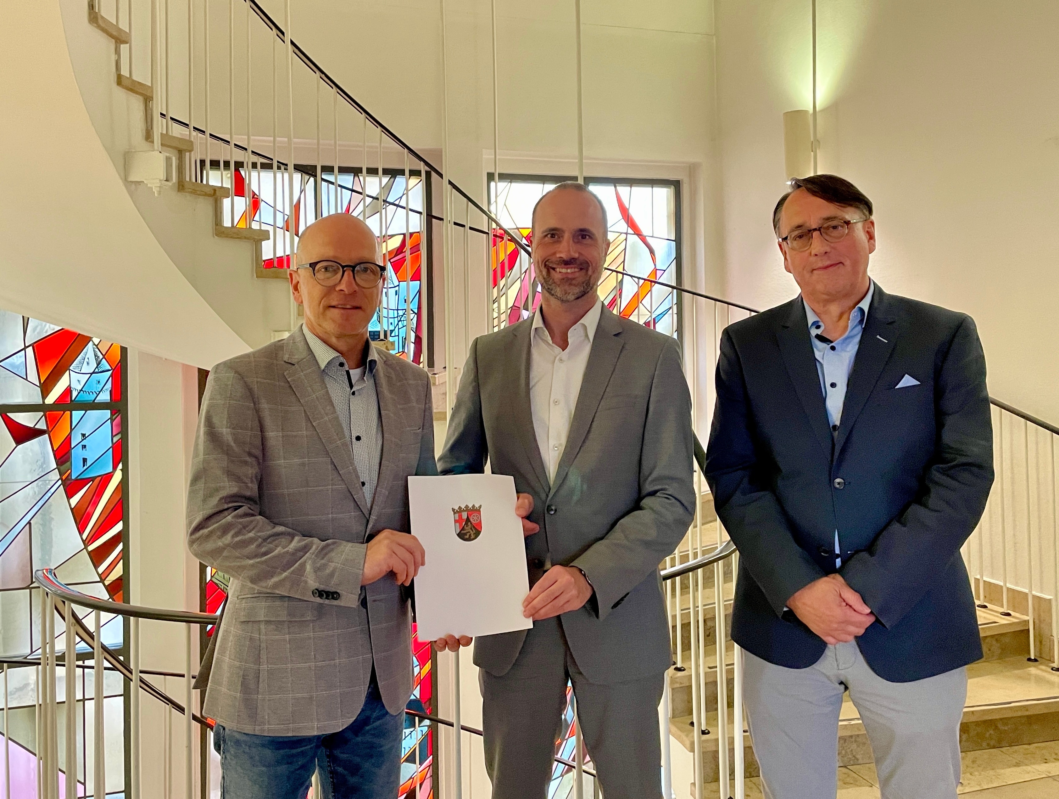 3 Herren mit einem Bescheid in den Händen