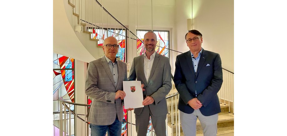 3 Herren mit einem Bescheid in den Händen