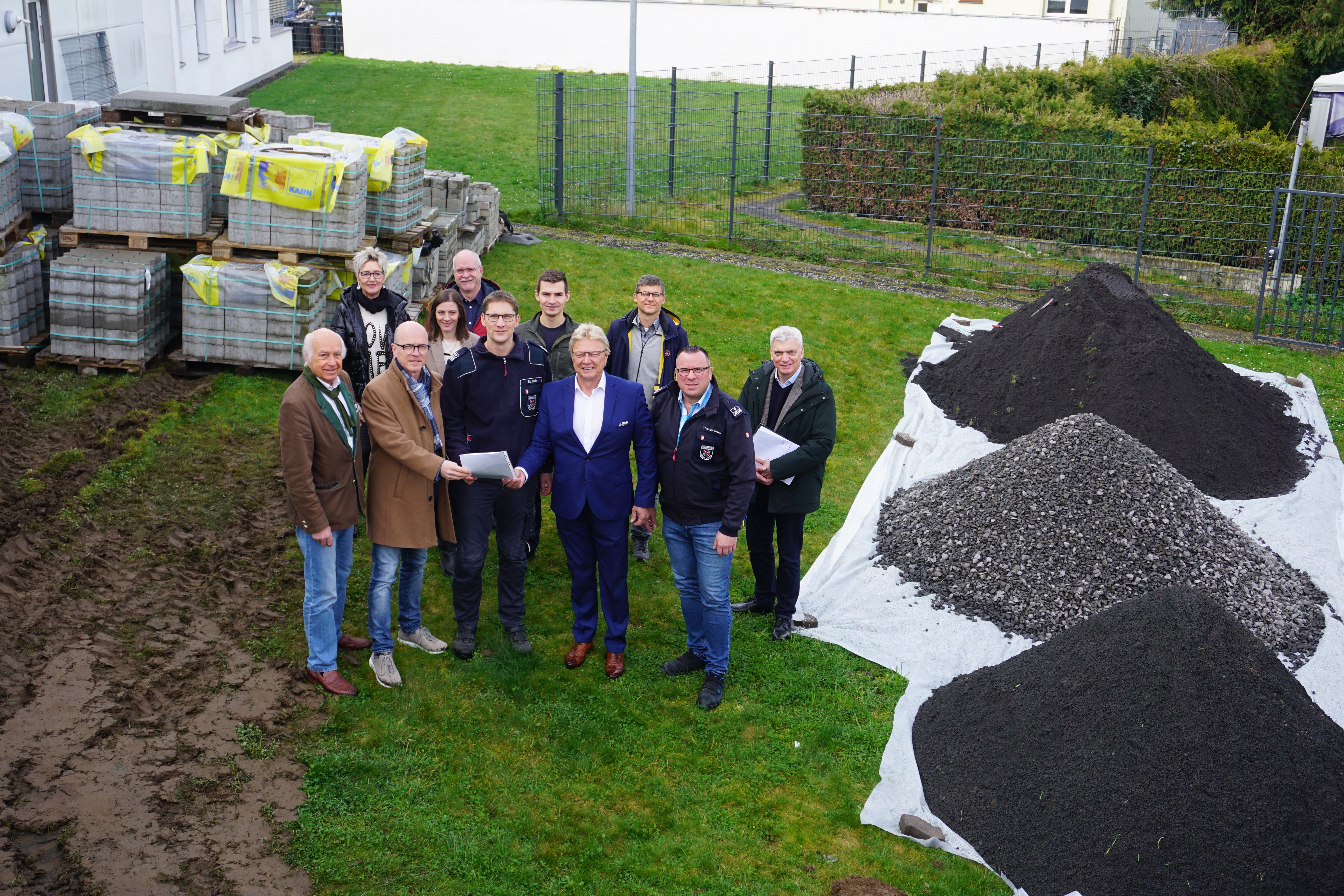 Vertreter der Stadt, der Stadtwerke, dem Architektenbüro und der Feuerwehr bei der Übergabe des Pachtvertrages Personengruppe steht für ein Bild zusammen - 2 Personen übergeben einen Vertrag