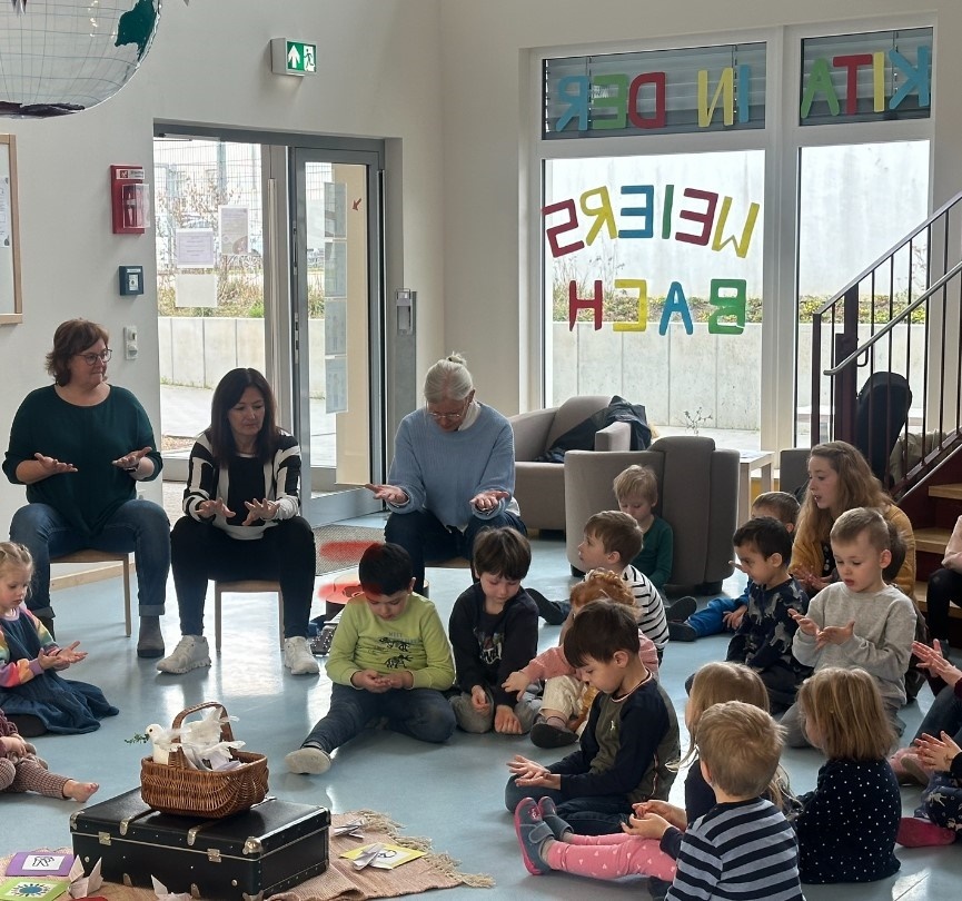 3 Erwachsene und mehrere Kinder bei der Handmeditation