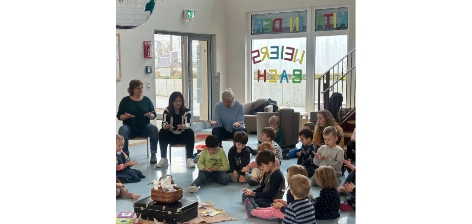 3 Erwachsene und mehrere Kinder bei der Handmeditation