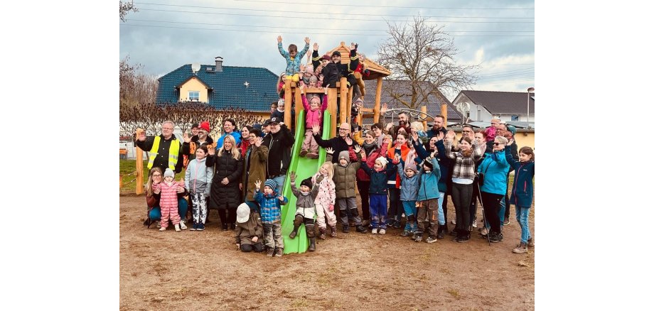 Viele Kinder stehen an einem neuen Klettergerüst für ein Bild zusammen