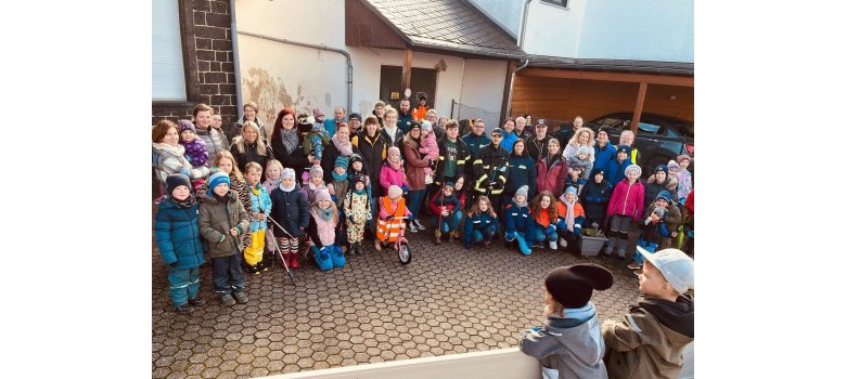 Eine Gruppe von Erwachsenen und Kindern stehen für ein Bild zusammen. Einige haben Greifzangen in der Hand