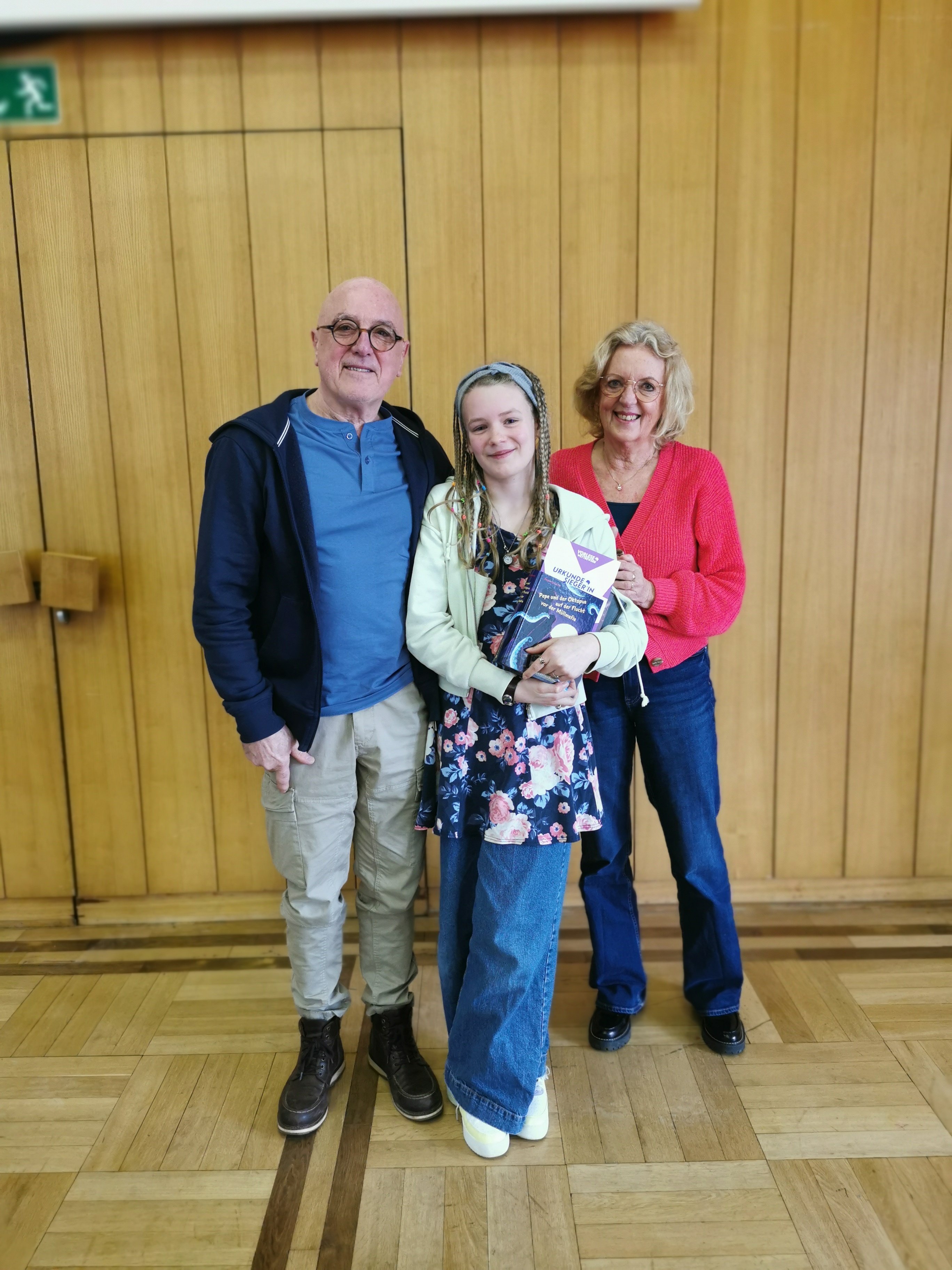 2 Erwachsene und ein Mädchen stehen für ein Bild zusammen