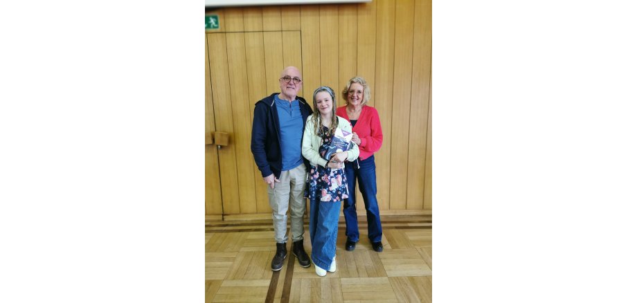 2 Erwachsene und ein Mädchen stehen für ein Bild zusammen