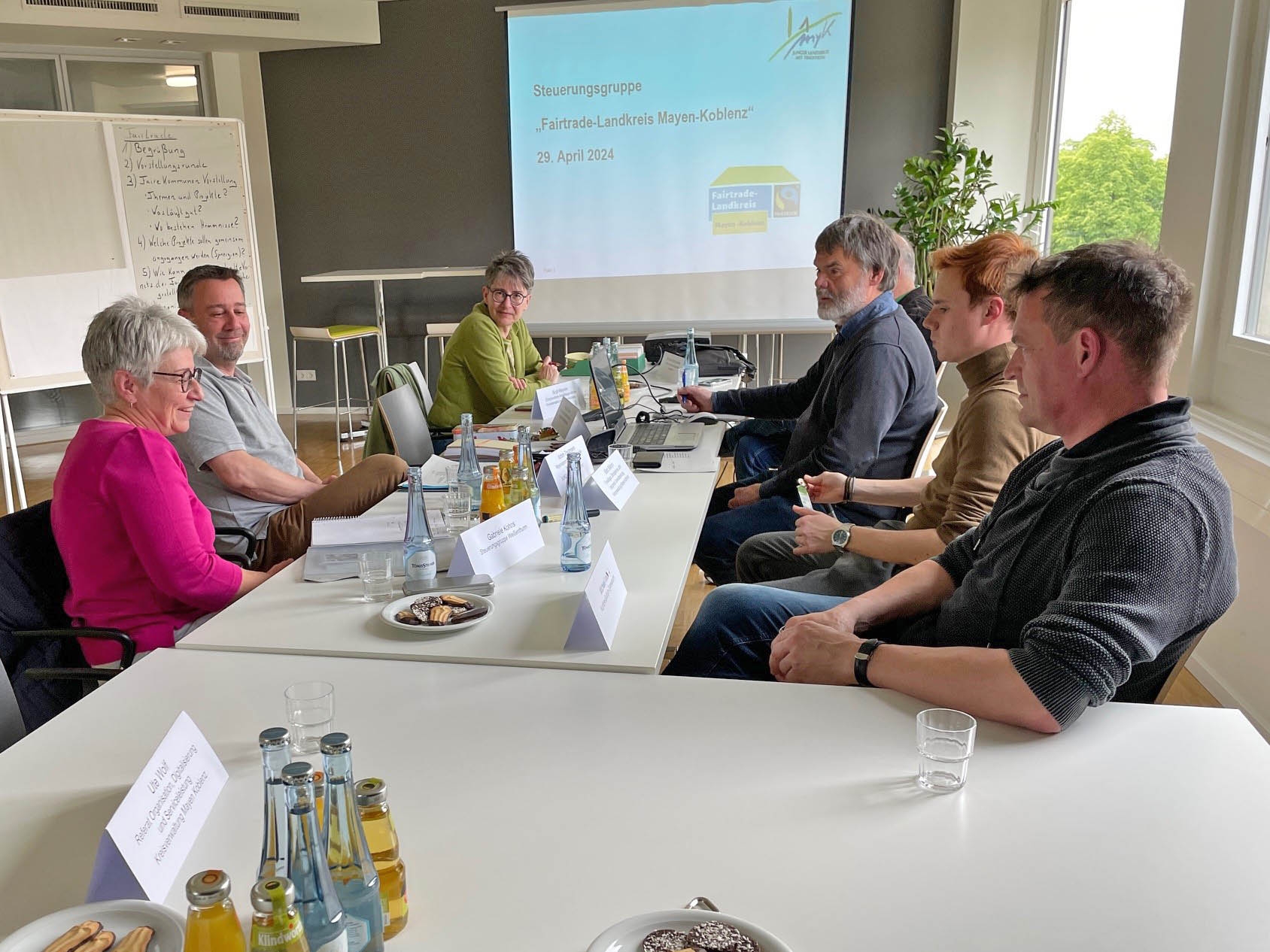 Die Mitglieder der einzelnen Fairtrade-Kommunen im Landkreis MYK trafen sich zum gegenseitigen Austausch im Kreishaus Mehrere Personen sitzen an einem Tisch und besprechen sich