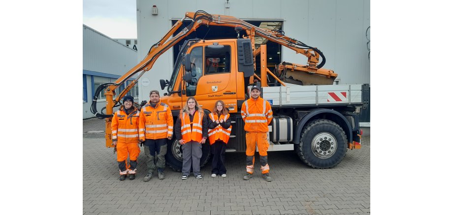 Zwei Schülerinnen und drei Mitarbeiter beim Betriebshof