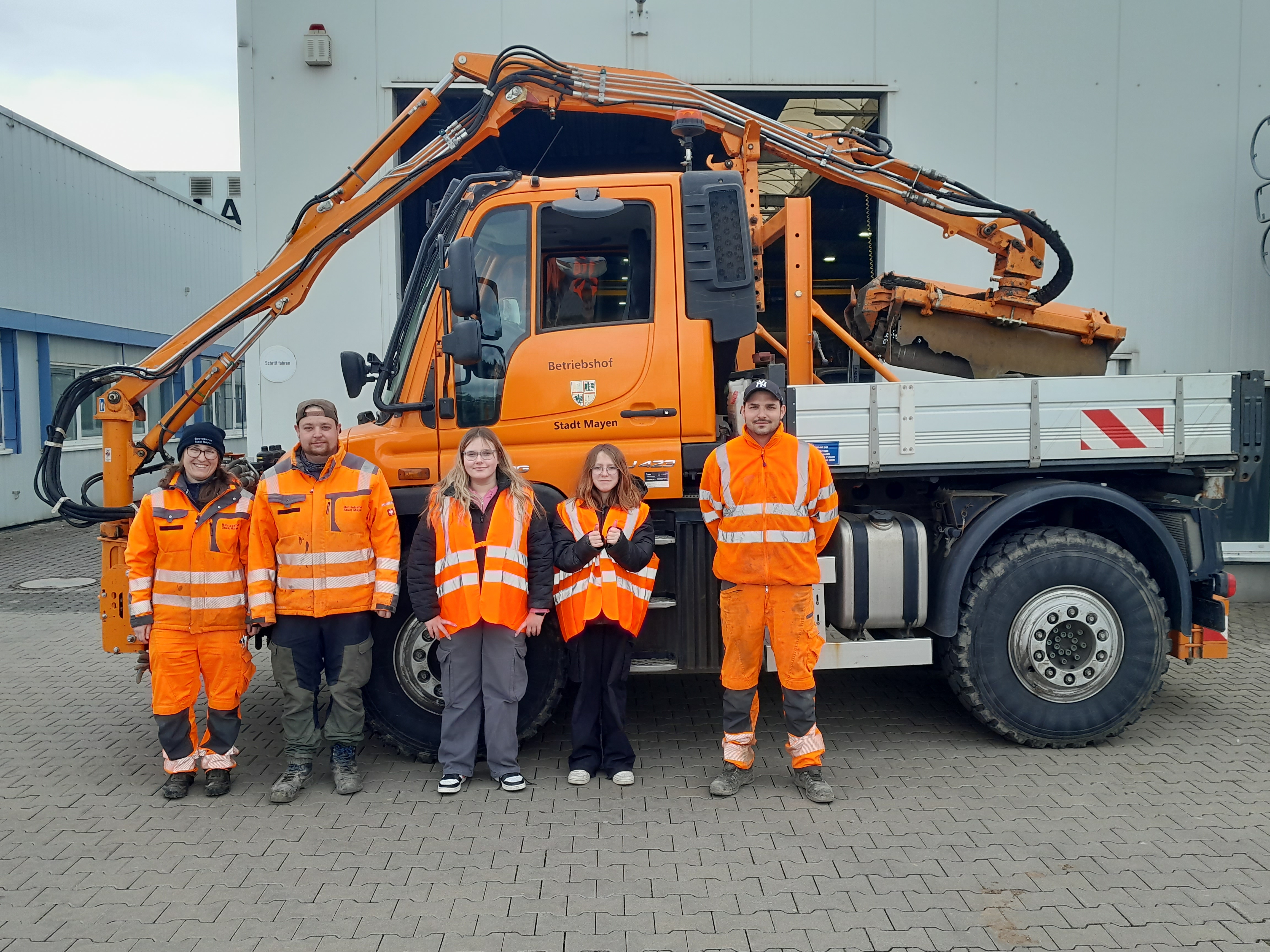 Zwei Schülerinnen und drei Mitarbeiter beim Betriebshof