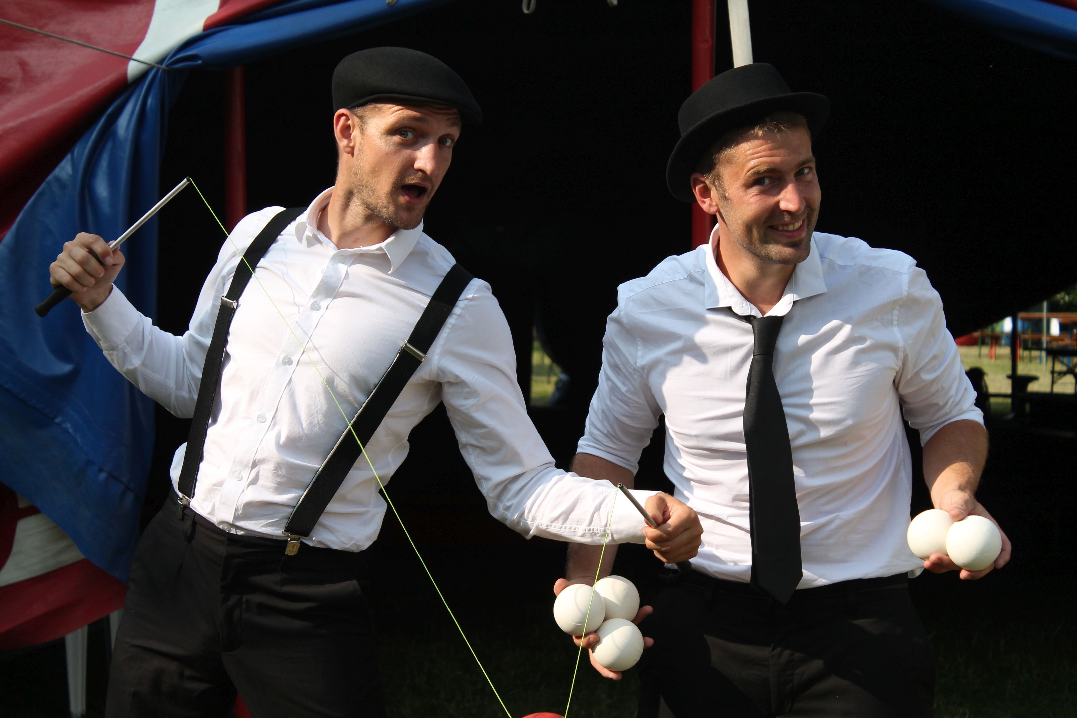 2 Männer mit weißem Hemd und schwarzen Hüten und Hosenträgern