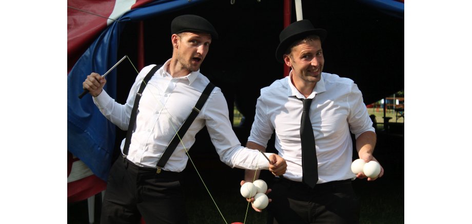 2 Männer mit weißem Hemd und schwarzen Hüten und Hosenträgern