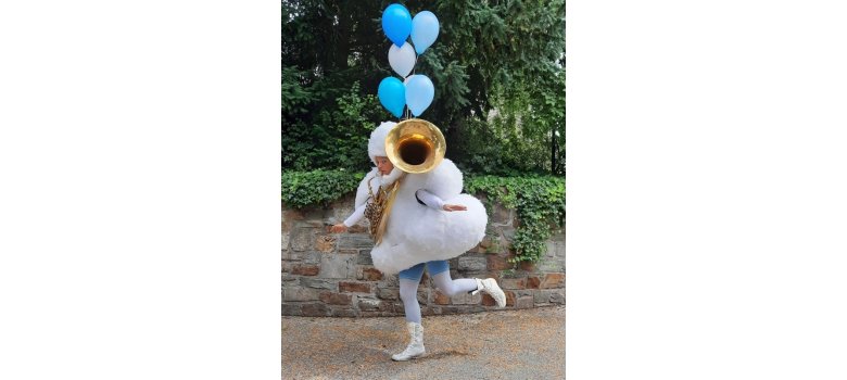 Frau in einem Wolkenkostüm, einem Instrument und Luftballons