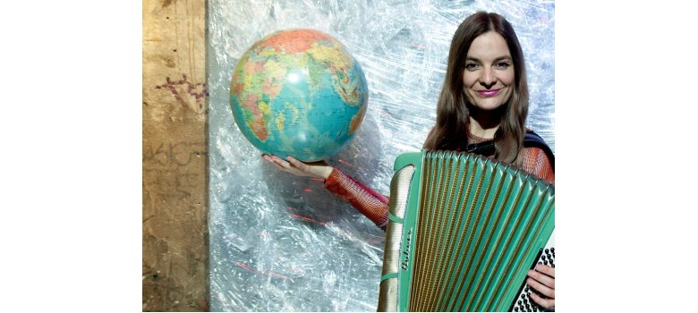 Frau mit einem Akkordeon und einer Weltkugel in den Händen