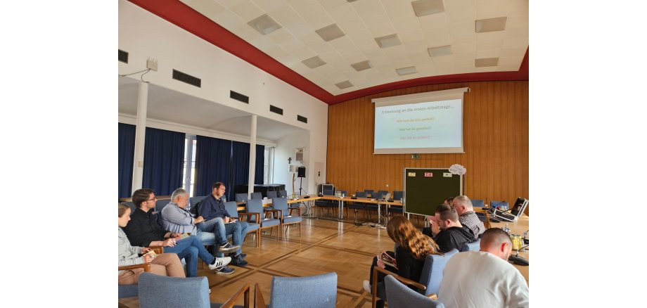Mehrere Personen sitzen vor einer Präsentation und erarbeiten Inhalte