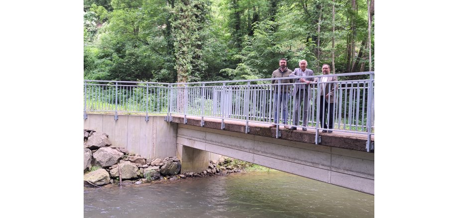 3 Personen stehen an einer Brücke