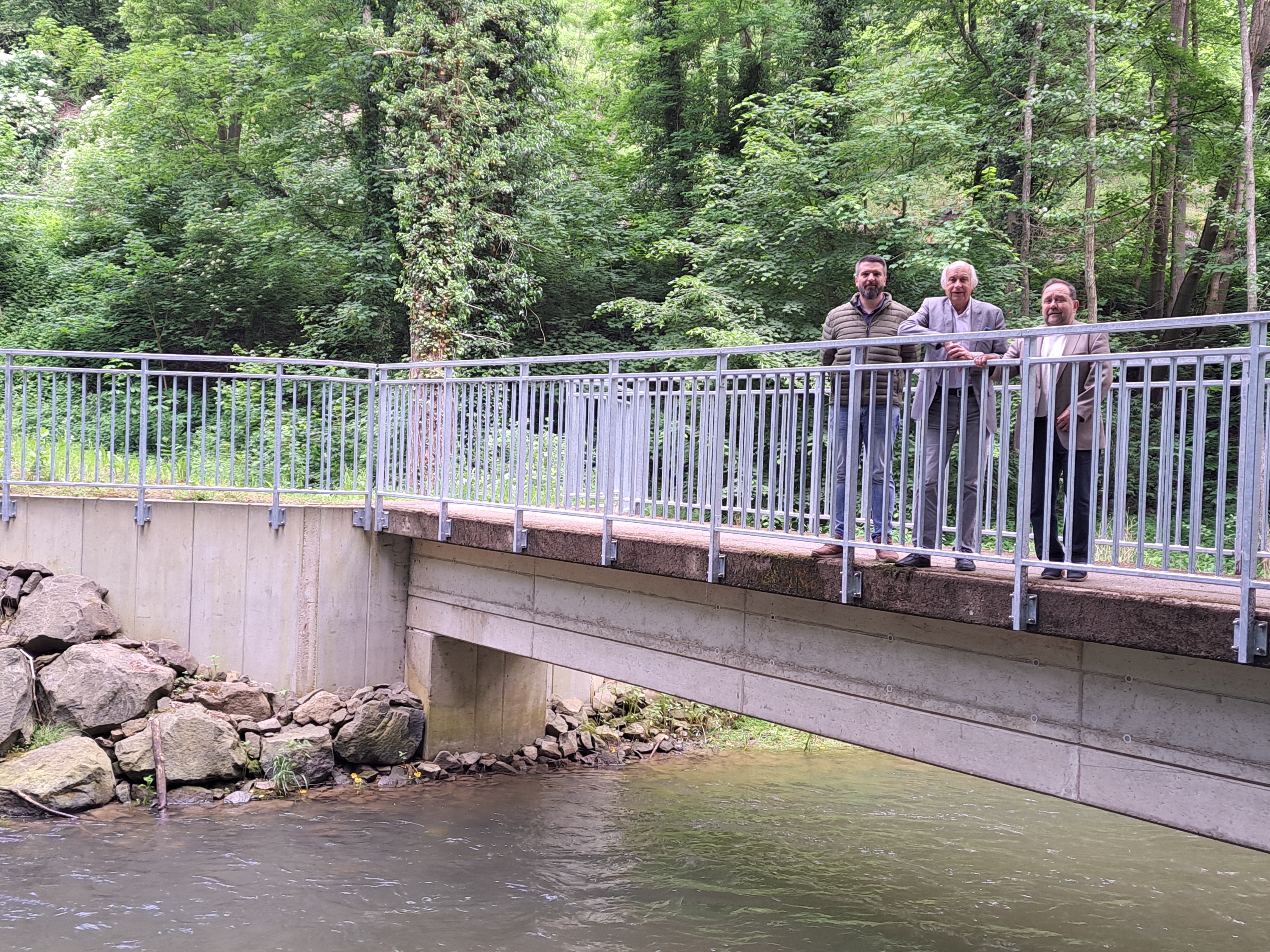 3 Personen stehen an einer Brücke