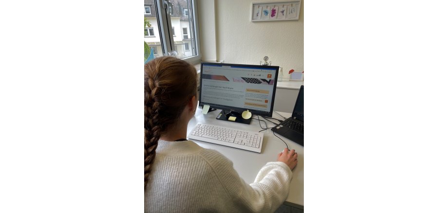 Frau sitzt am Computer und informiert sich über die Onlinedienstleistungen der Stadt Mayen