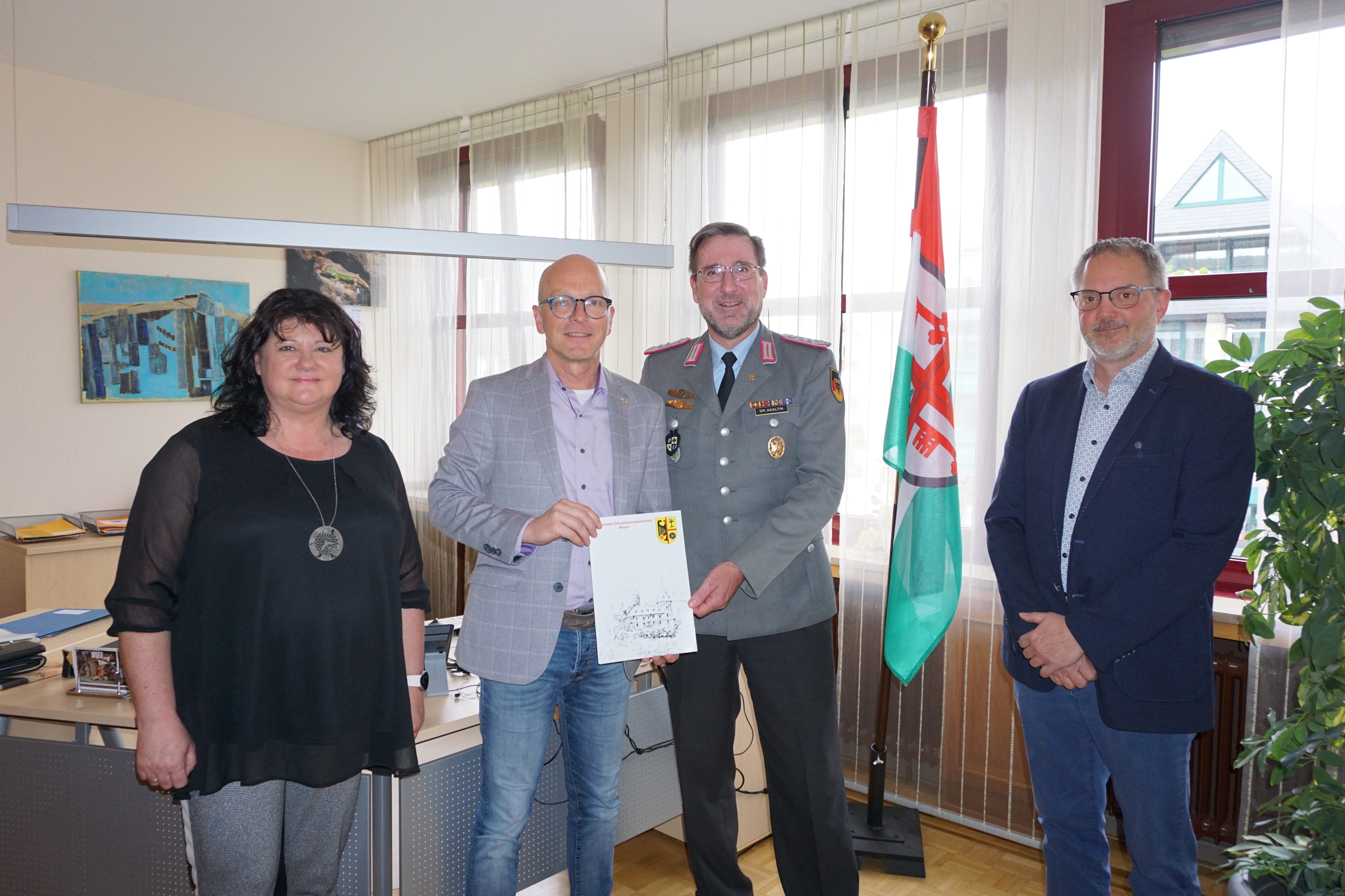 Eine Frau und drei Herren stehen für ein Bild zusammen - 2 davon halten einen Vertrag in den Händen