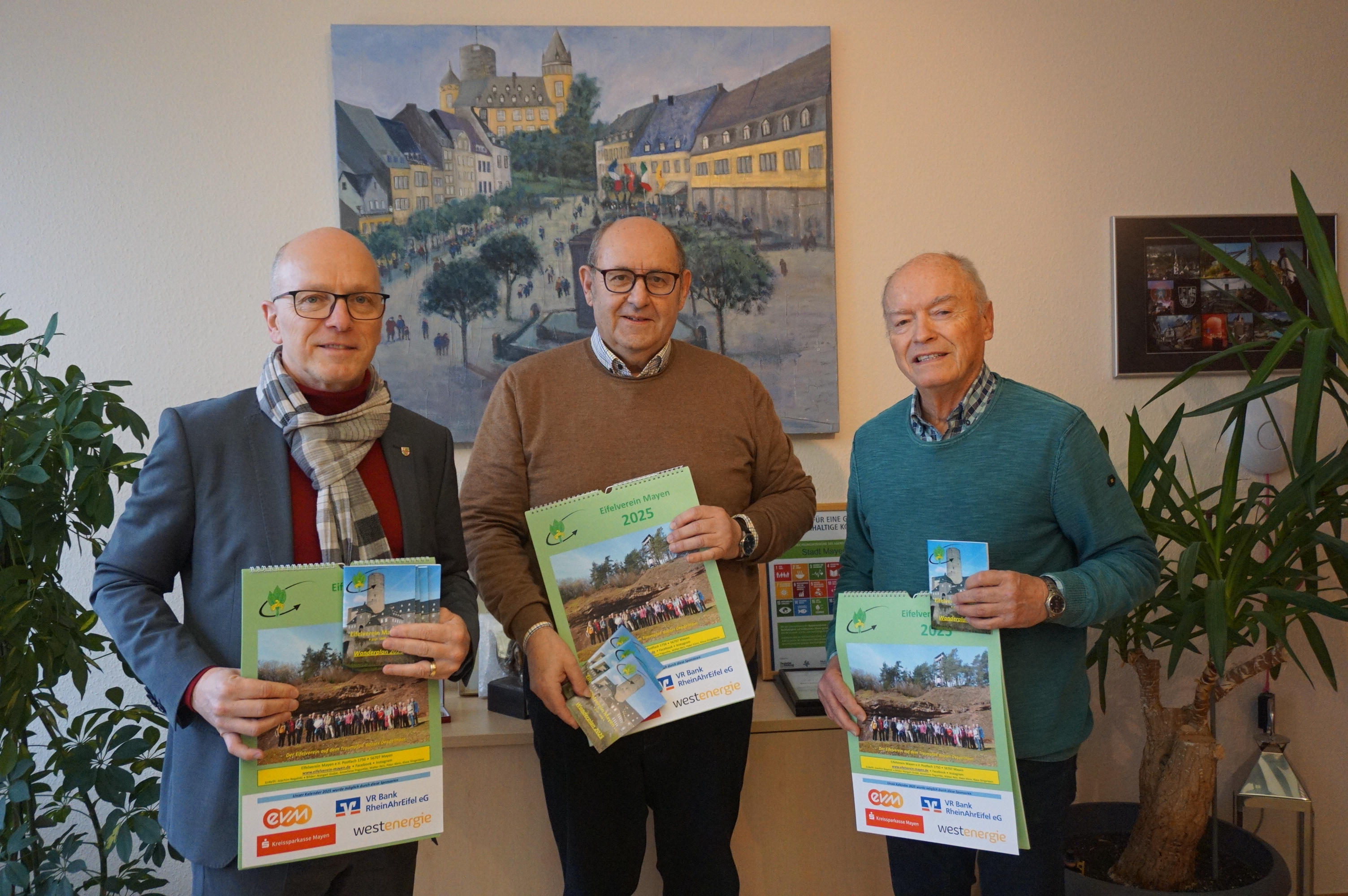 Joachim Rogalski (Mitte) und Walter Reis (rechts) übergeben den Wanderplan 2025 an Oberbürgermeister Dirk Meid
