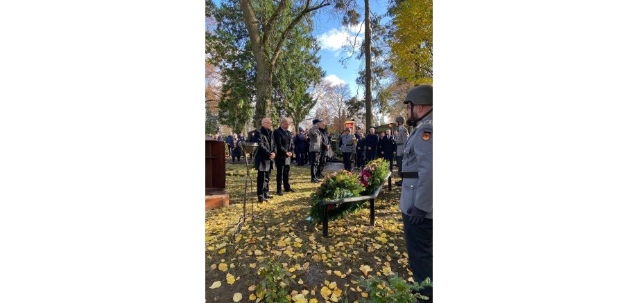 Personen in Uniform stehen auf dem Friedhof