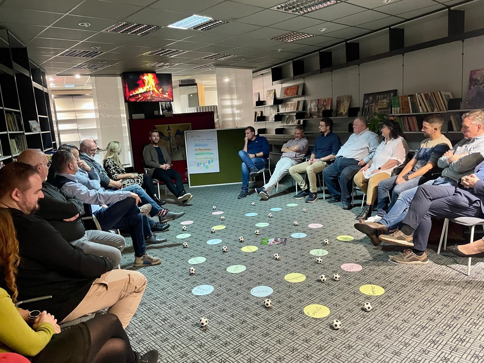 Mehrere Personen sitzen in einem Stuhlkreis zusammen - in der Mitte liegen verschiedene Gegenstände