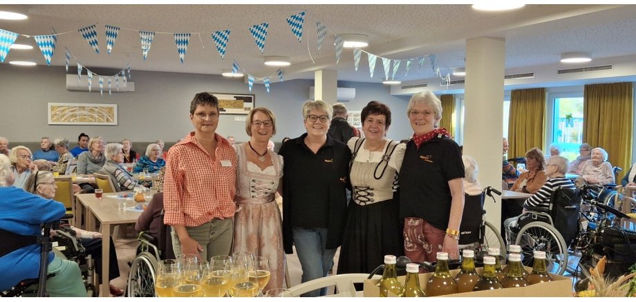 Fünf Frauen, teilweise in Tracht stehen für ein Bild zusammen - im Hintergrund ein voller Saal