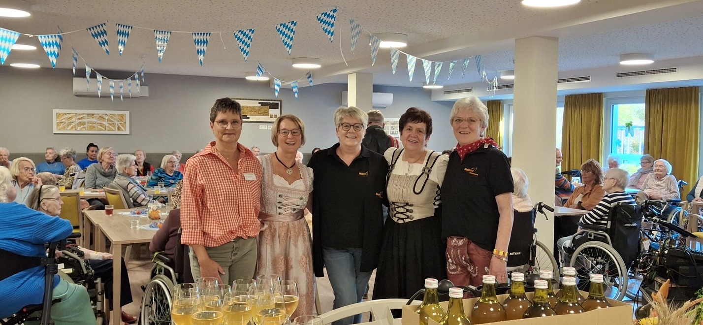 Fünf Frauen, teilweise in Tracht stehen für ein Bild zusammen - im Hintergrund ein voller Saal