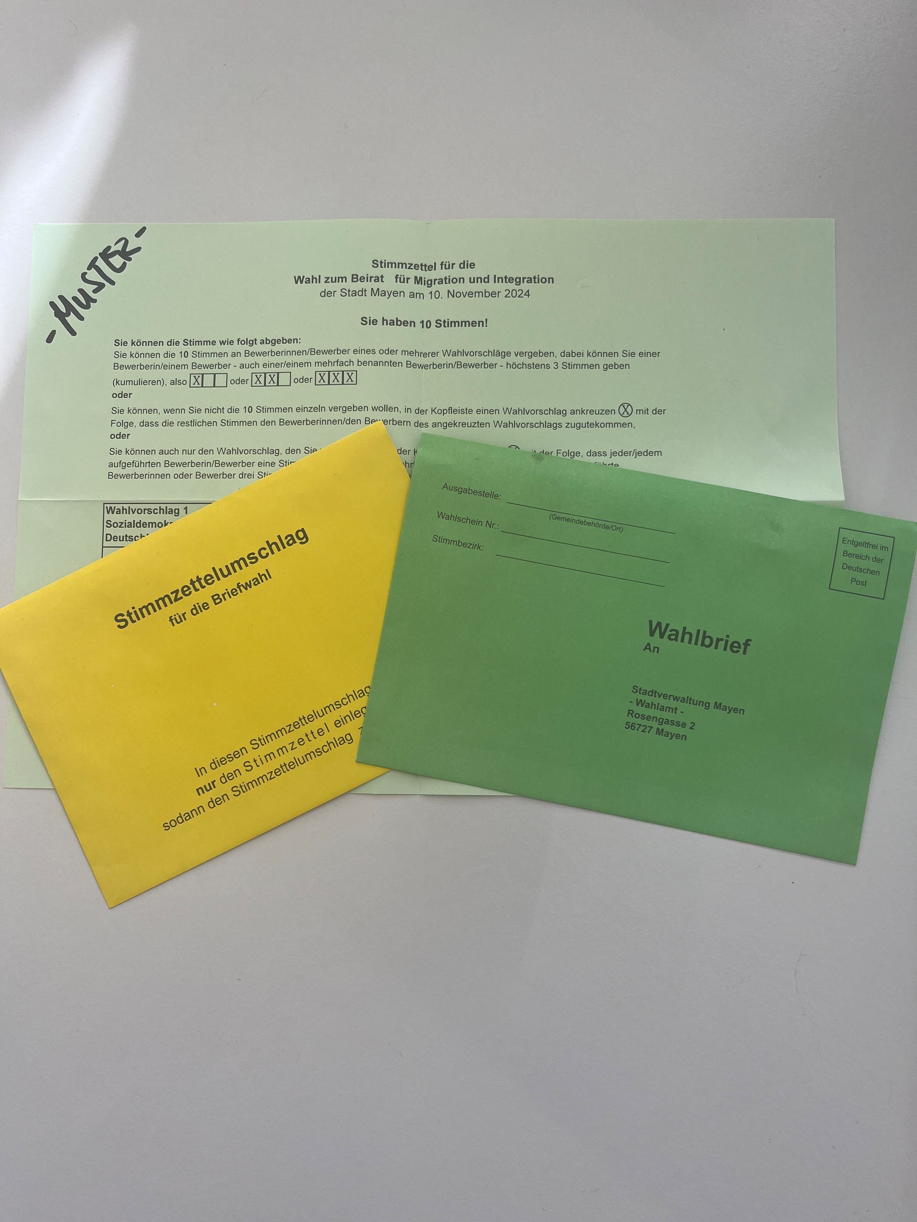 Ein Stimmzettel und zwei Umschläge in gelb und grün