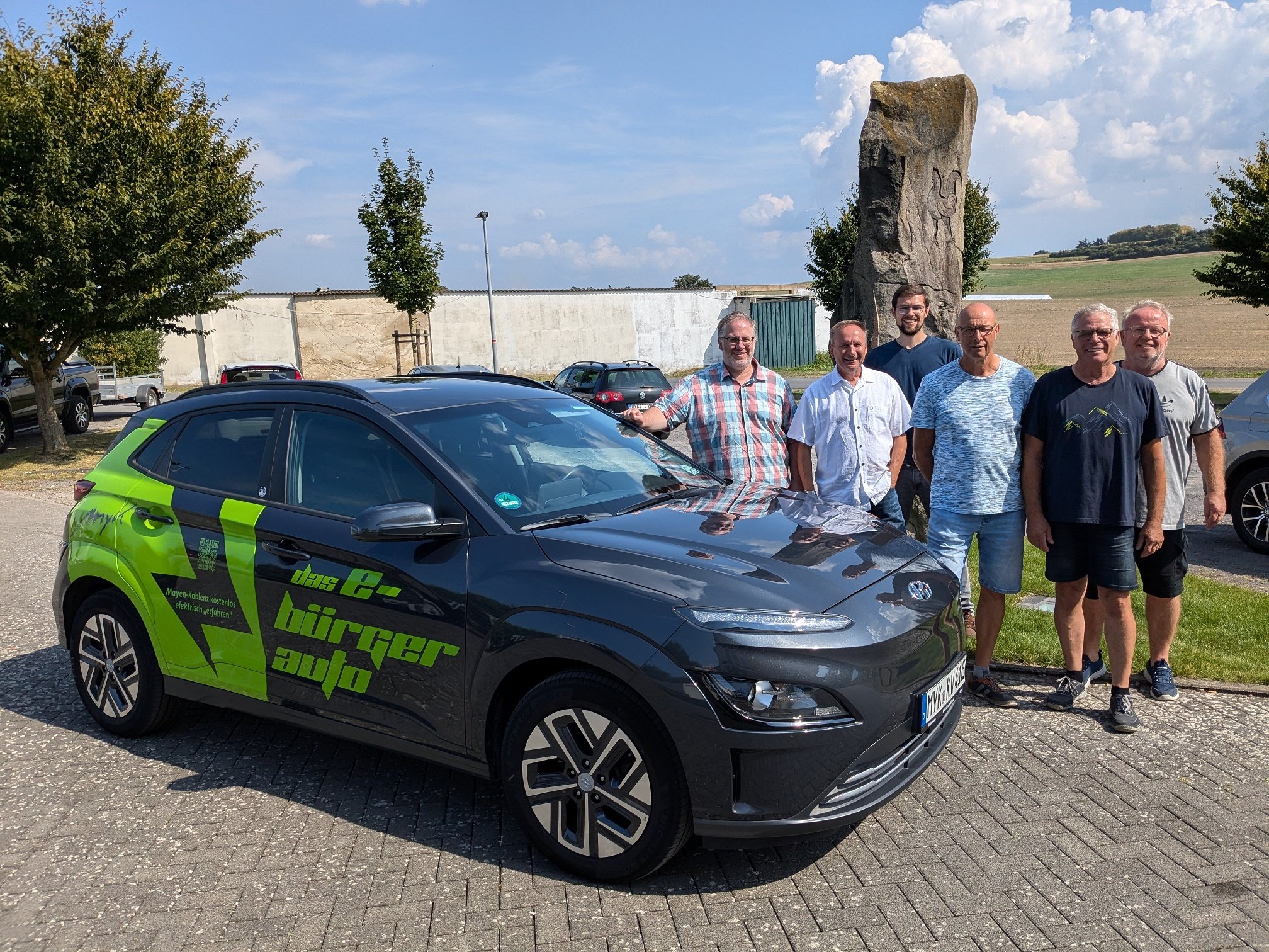 6 Männer stehen neben einem E-Auto