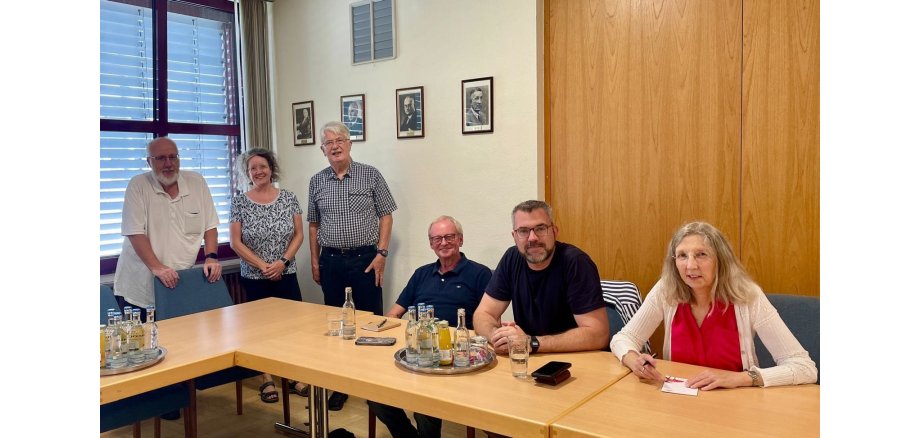 Die Steuerungsgruppe konnte auch in dieser Sitzung wieder neue Ideen sammeln, wie man auf das Thema Fairtrade aufmerksam macht 6 Personen sitzen oder stehen in einem Beratungszimmer zusammen