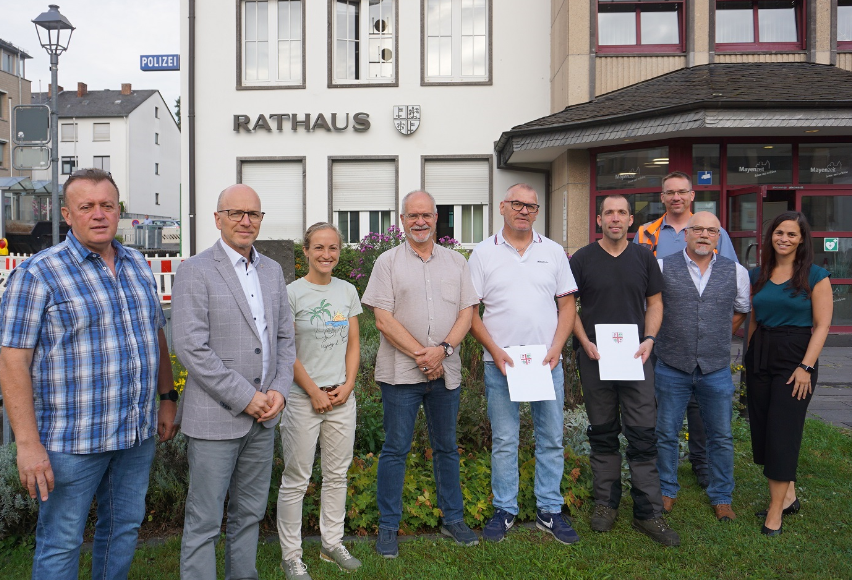 9 Personen stehen vor dem Rathaus