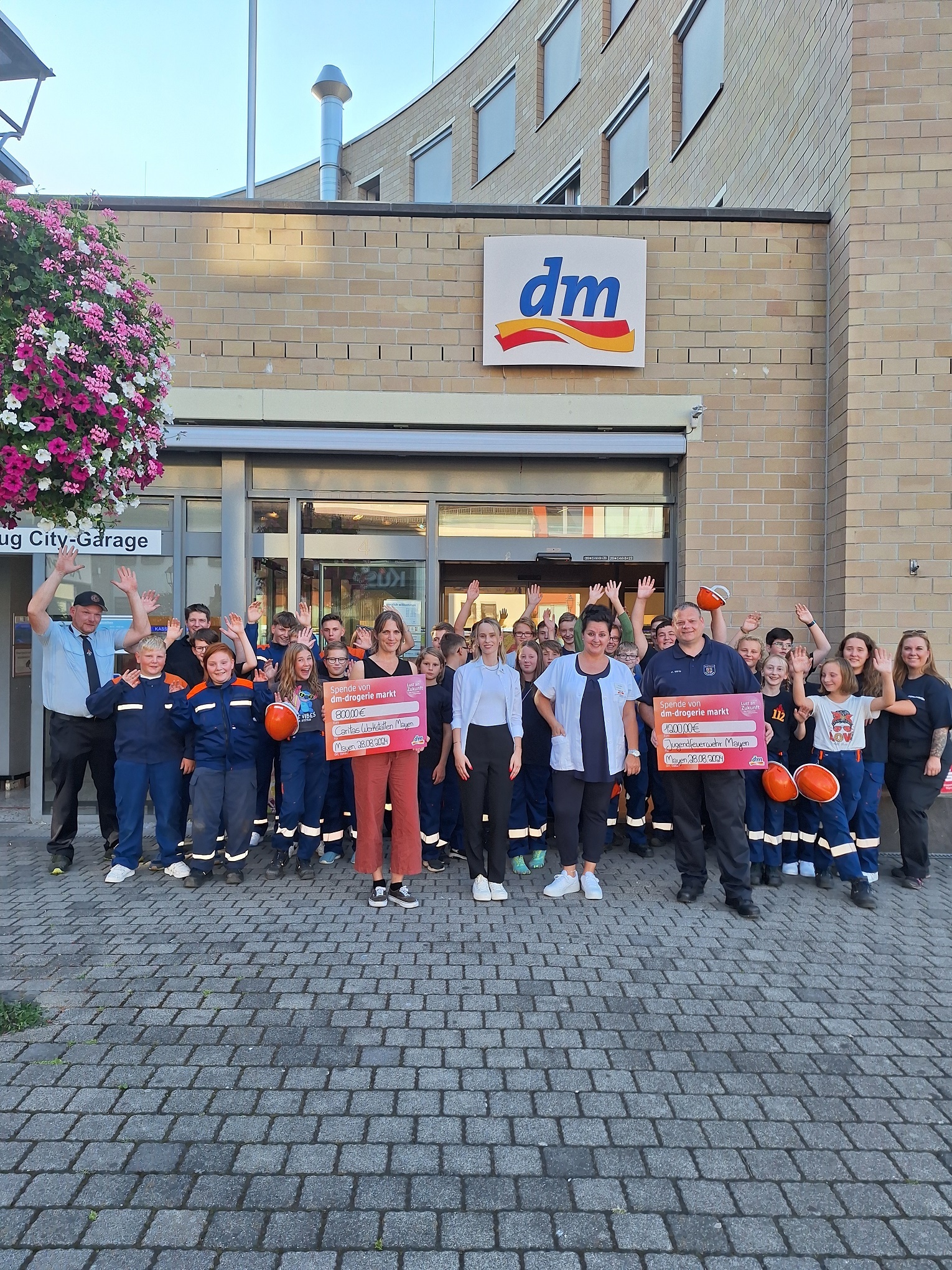 Eine Gruppe von Kindern und Erwachsenen steht vor einer DM Filiale