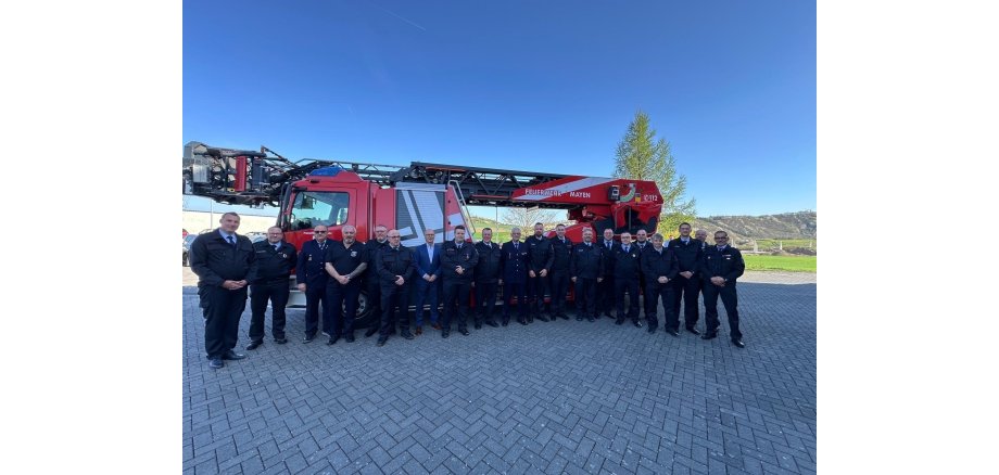 Männer in Uniform stehen vor einem Feuerwehrauto