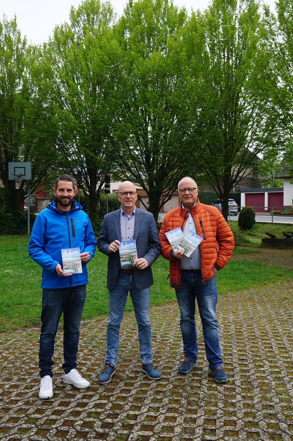 3 Personen stehen zusammen und halten eine Broschüre in den Händen