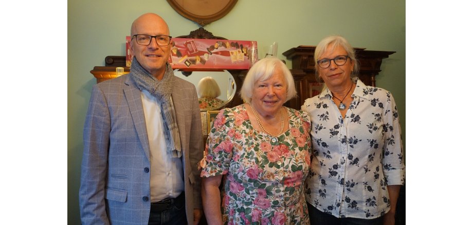 Zwei Frauen und ein Mann stehen für ein Foto zusammen