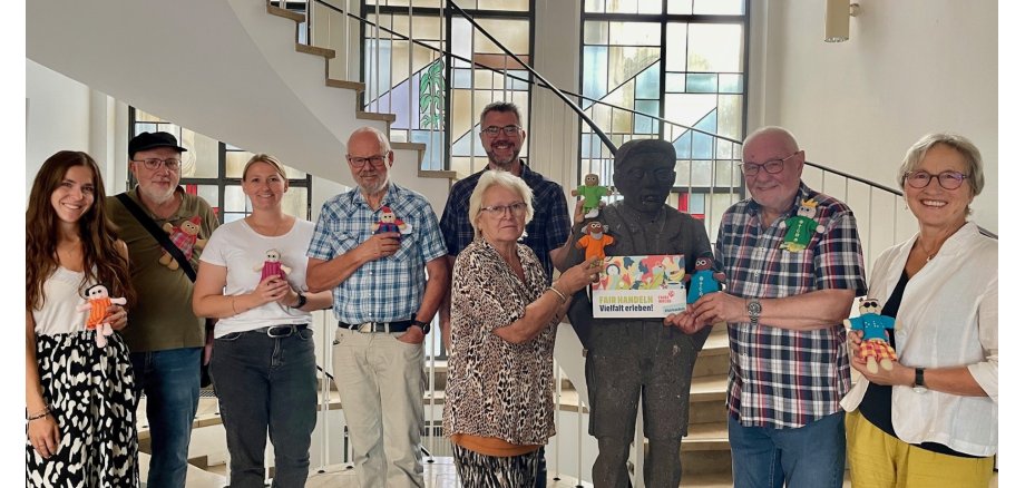 Eine Gruppe von Menschen steht für ein Foto zusammen - alle halten eine Puppe in der Hand